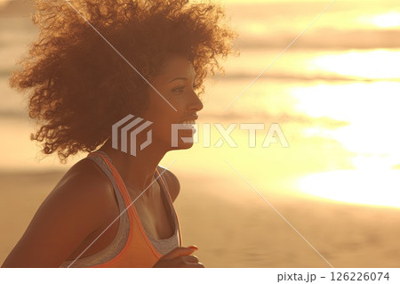 Portrait of a young woman running on the beach during sunset. The woman joyfully runs along the beach, her spirit captured against the breathtaking colors of the sunset. 126226074