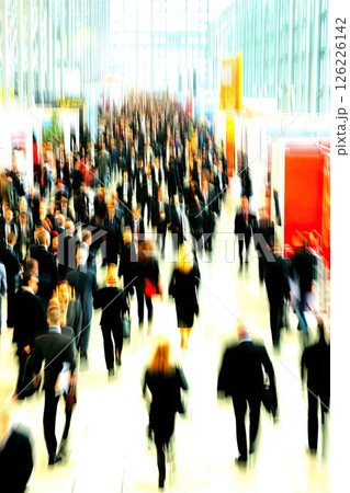 A blurry crowd of business people in a large, bright business hall. A large business hall is filled with a blurry crowd, creating an atmosphere of innovation and collaboration among professionals. 126226142