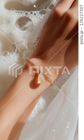 A detailed artistic close-up of a hand adorned with gold jewelry amidst a bubble-laden surface, emphasizing elegance and softness with a luxurious feel. Jewelry, lifestyle, and beauty themes. 126227307
