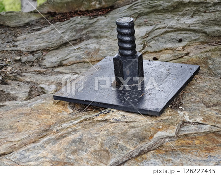 Plate and anchor bolt. Structural support on natural stone with gap to plate and anchor bolt in rocky base Plate and anchor bolt. Structural support on natural stone with gap to plate and anchor bolt in rocky base 126227435