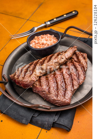 Grilled Denver steak, perfectly seared with beautiful grill marks, showcasing its juicy tenderness and rich flavor. orange background. top view Grilled Denver steak, perfectly seared with beautiful grill marks, showcasing its juicy tenderness and rich flavor. orange background. top view 126228184