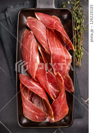 Dry cured and smoked serrano ham, pork meat. black background. top view Dry cured and smoked serrano ham, pork meat. black background. top view 126228185
