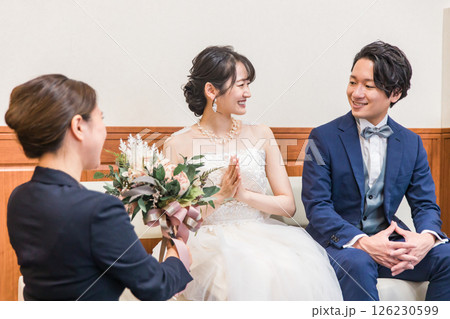 結婚式場のブライズルーム・控室で花束・ブーケを持つ新郎新婦の男女(ドレス試着・衣装合わせ) 126230599