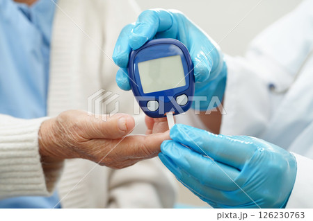 Asian doctor using digital glucose meter for check sample blood sugar level to treatment diabetes. 126230763