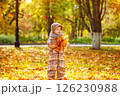 Happy child is holding heap of maple leaves at golden autumn park background. 126230988