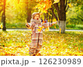 Happy child is throwing heap of maple leaves at golden autumn park background. 126230989