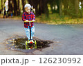 Portrait of little boy riding scooter at summer park outdoors background. 126230992