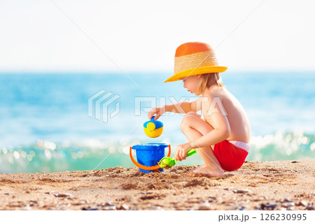 Happy child is playing with toys at sea shore background. Happy child is playing with toys at sea shore background. 126230995