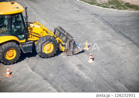 Modern yellow forklift stands on the road near the dug up road. Concept of emergency service for elimination of accident in water supply and sewerage. Copy space for text 126232931