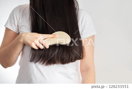 Girl holding massage comb on black hair background. Wet and tangled hair care, close-up. Copy space for text. Hair care Girl holding massage comb on black hair background. Wet and tangled hair care, close-up. Copy space for text. Hair care 126233551
