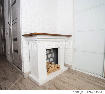 Modern stylish fireplace with handmade firewood on a white background in the corridor. Beautiful interior. Copy space for text 126233561