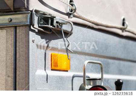 orange reflector on the side of a galvanized trailer body, close-up orange reflector on the side of a galvanized trailer body, close-up 126233618