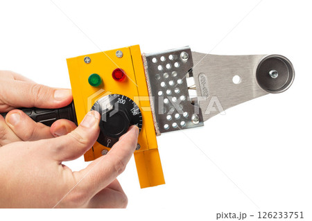 adjusting the temperature in a yellow soldering iron for soldering polypropylene pipes on a white background, isolate, close-up 126233751