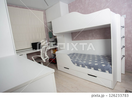 A bunk bed with a ladder in a children's modern bedroom with white furniture and interior, close-up A bunk bed with a ladder in a children's modern bedroom with white furniture and interior, close-up 126233783