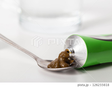 Urological paste on herbs against the background of a glass of water. Treatment of infectious inflammatory diseases of the urinary system, close-up Urological paste on herbs against the background of a glass of water. Treatment of infectious inflammatory diseases of the urinary system, close-up 126233818