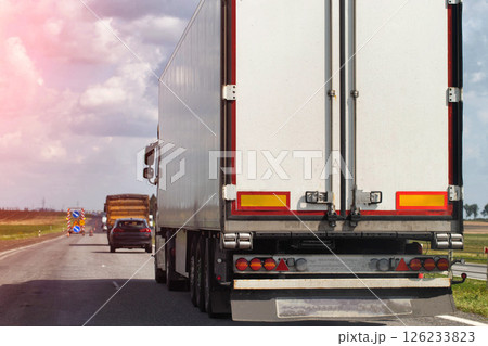 A truck with a semi-trailer delivers cargo along the highway to the marketplace. Delivery service from an online store to the buyer. Copy space for text A truck with a semi-trailer delivers cargo along the highway to the marketplace. Delivery service from an online store to the buyer. Copy space for text 126233823