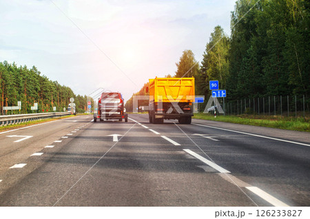 Transporting an SUV car on a carriage along a country road in the summer against the backdrop of the sun. Carriage rental services. Copy space for text 126233827