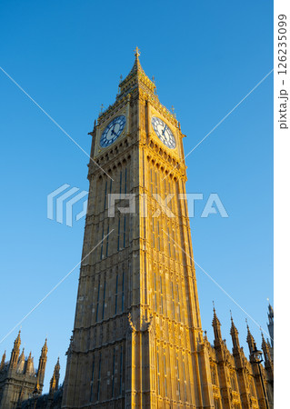Big Ben, a prominent clock tower in London, displays its iconic structure under a bright blue sky. Visitors and locals admire this historic landmark during a sunny day. Big Ben, a prominent clock tower in London, displays its iconic structure under a bright blue sky. Visitors and locals admire this historic landmark during a sunny day. 126235099