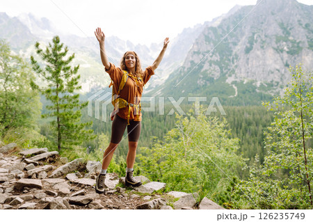 Young traveler woman with a yellow backpack on a cliff. Sports concept, traveler. Active lifestyle. 126235749