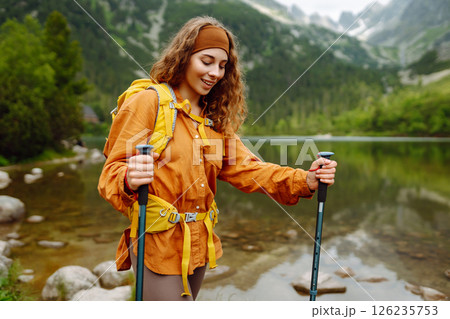 Travel Slovakia, Europe. Tourist with a yellow backpack stands against the backdrop of alpine lake. Travel Slovakia, Europe. Tourist with a yellow backpack stands against the backdrop of alpine lake. 126235753
