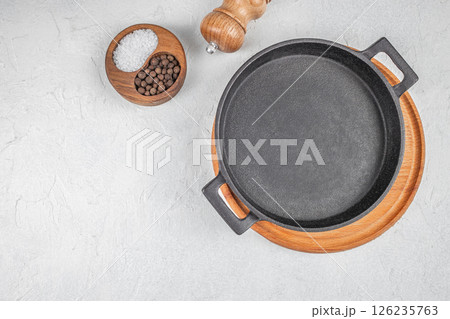 Empty cast iron frying pan on dark grey culinary background, top view. copy space 126235763