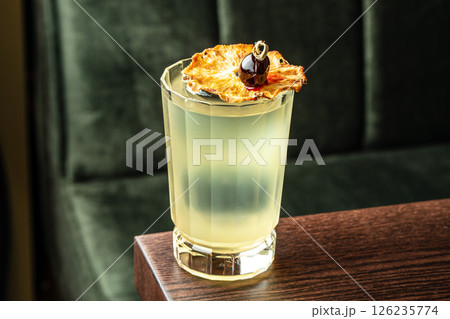 Light yellow cocktail with ice and dried pineapple slice. Alcoholic cocktail Almond Whiskey Sour from whiskey Light yellow cocktail with ice and dried pineapple slice. Alcoholic cocktail Almond Whiskey Sour from whiskey 126235774