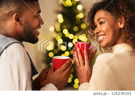 Loving african-american couple drinking tea in front of Christmas tree and enjoying winter holidays Loving african-american couple drinking tea in front of Christmas tree and enjoying winter holidays 126236101
