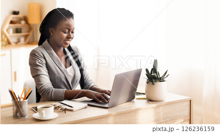 Successful businesslady working on laptop in modern office, typing on keyboard and smiling, free space Successful businesslady working on laptop in modern office, typing on keyboard and smiling, free space 126236159