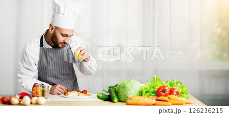 Chef Guy Cooking Fish Squeezing Lemon Juice On Roasted Salmon Steak Standing In Restaurant Kitchen. Selective Focus Chef Guy Cooking Fish Squeezing Lemon Juice On Roasted Salmon Steak Standing In Restaurant Kitchen. Selective Focus 126236215