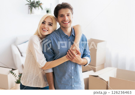 Moving New House. Happy Young Couple Hugging Posing Among Packed Boxes In Own Flat. Empty Space 126236463