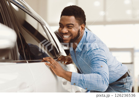 Happy Car Owner. African Guy Touching His New Vehicle Excited About Buying Automobile In Dealership Showroom. Selective Focus Happy Car Owner. African Guy Touching His New Vehicle Excited About Buying Automobile In Dealership Showroom. Selective Focus 126236536