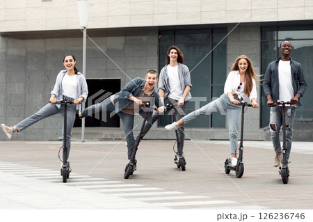 Modern Generation Concept. Five trendy teenagers having fun, riding electric push scooters, fooling around Modern Generation Concept. Five trendy teenagers having fun, riding electric push scooters, fooling around 126236746