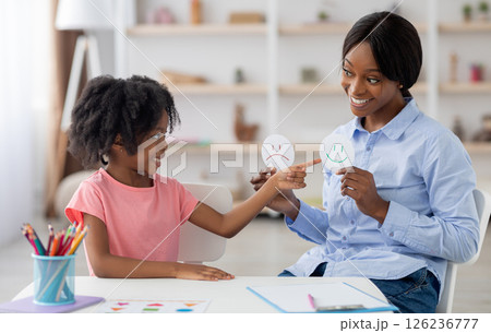 Female teacher friendly pretty young black woman and little girl preschooler exercising at daycare, learning about emotions, copy space. Child development, emotional intelligence for kids concept 126236777