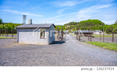 The memorial in Lesetice, Czechia, honors victims of communism. It features a former prison building with a clear path leading to the memorial site, surrounded by nature. 126237414
