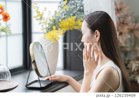鏡でお肌のチェックをする笑顔の女性 鏡でお肌のチェックをする笑顔の女性 126239409