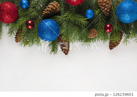 christmas card on a light gray background, branches of a Christmas tree with cones and ornament ball in red and blue colors 126239601