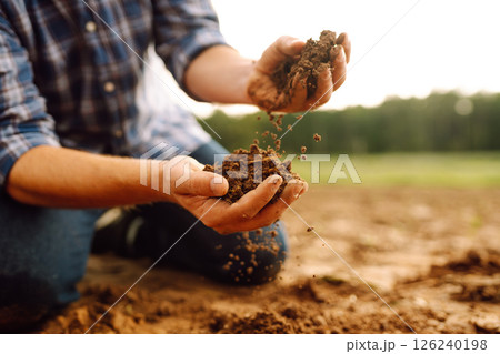 Soil is in the strong hands of a farmer on a black field. Agriculture or gardening concept. Soil is in the strong hands of a farmer on a black field. Agriculture or gardening concept. 126240198