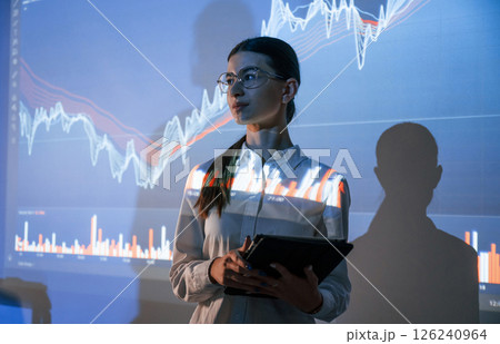 Woman is standing near projector with the finance graphs Woman is standing near projector with the finance graphs 126240964