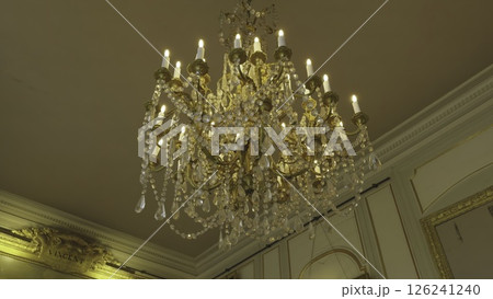 Elegant crystal chandelier illuminating ornate palace room. Action Elegant crystal chandelier illuminating ornate palace room. Action 126241240
