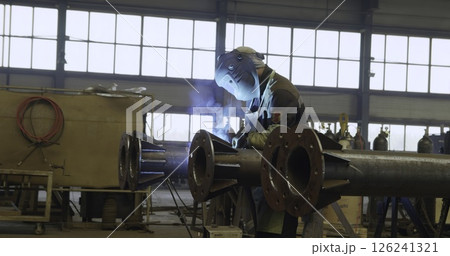 An Industrial Worker Wearing Protective Gear in a Workshop Environment While Working. Media An Industrial Worker Wearing Protective Gear in a Workshop Environment While Working. Media 126241321