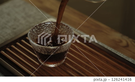 Pouring tea into a textured glass cup creates a calm atmosphere and showcases handcrafted luxury. Media 126241416