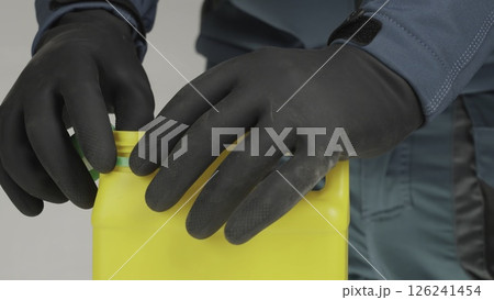 Careful and Professional Handling of the Yellow Bottle using Protective Gloves and Gear. Creative 126241454