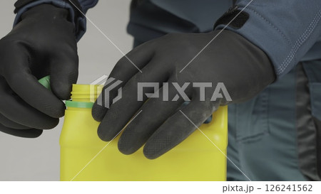 Careful and Professional Handling of the Yellow Bottle using Protective Gloves and Gear. Creative 126241562