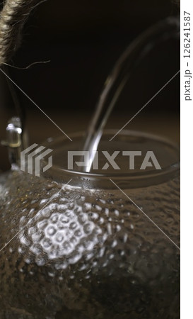 An Elegant Water Pouring into a Beautiful Glass Teapot with Grace and Refinement. Media 126241587