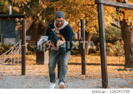 On the playground. Father and young son is together outdoors at daytime On the playground. Father and young son is together outdoors at daytime 126241730