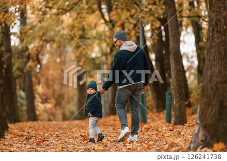 Holding each other by the hands. Father and young son is together outdoors at daytime 126241738