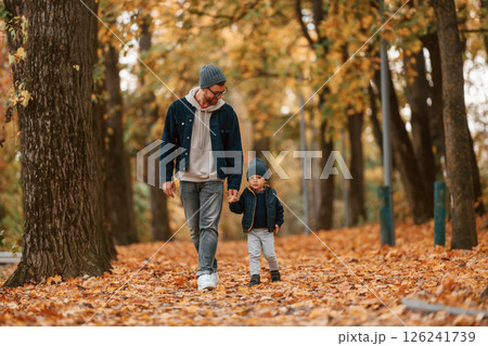 Holding each other by the hands. Father and young son is together outdoors at daytime 126241739