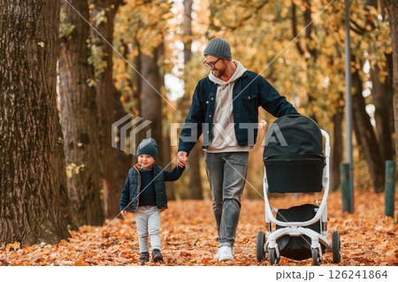 With pram. Father and young son is together outdoors at daytime With pram. Father and young son is together outdoors at daytime 126241864