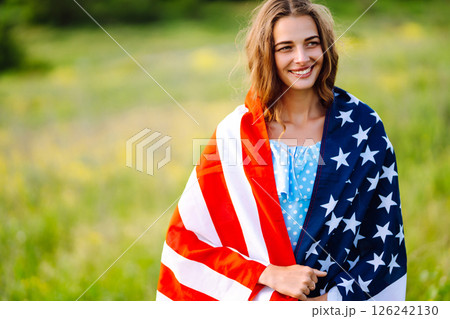 Young woman with american USA flag on blooming meadow. Independence Day, 4th July. Young woman with american USA flag on blooming meadow. Independence Day, 4th July. 126242130