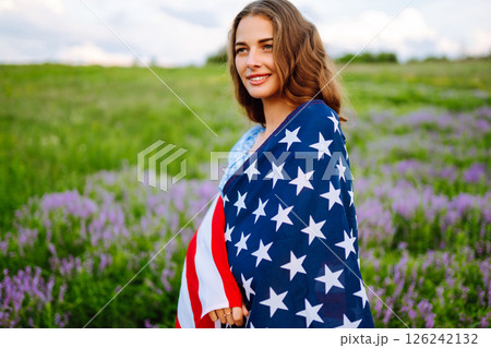 Young woman with american USA flag on blooming meadow. Independence Day, 4th July. Young woman with american USA flag on blooming meadow. Independence Day, 4th July. 126242132